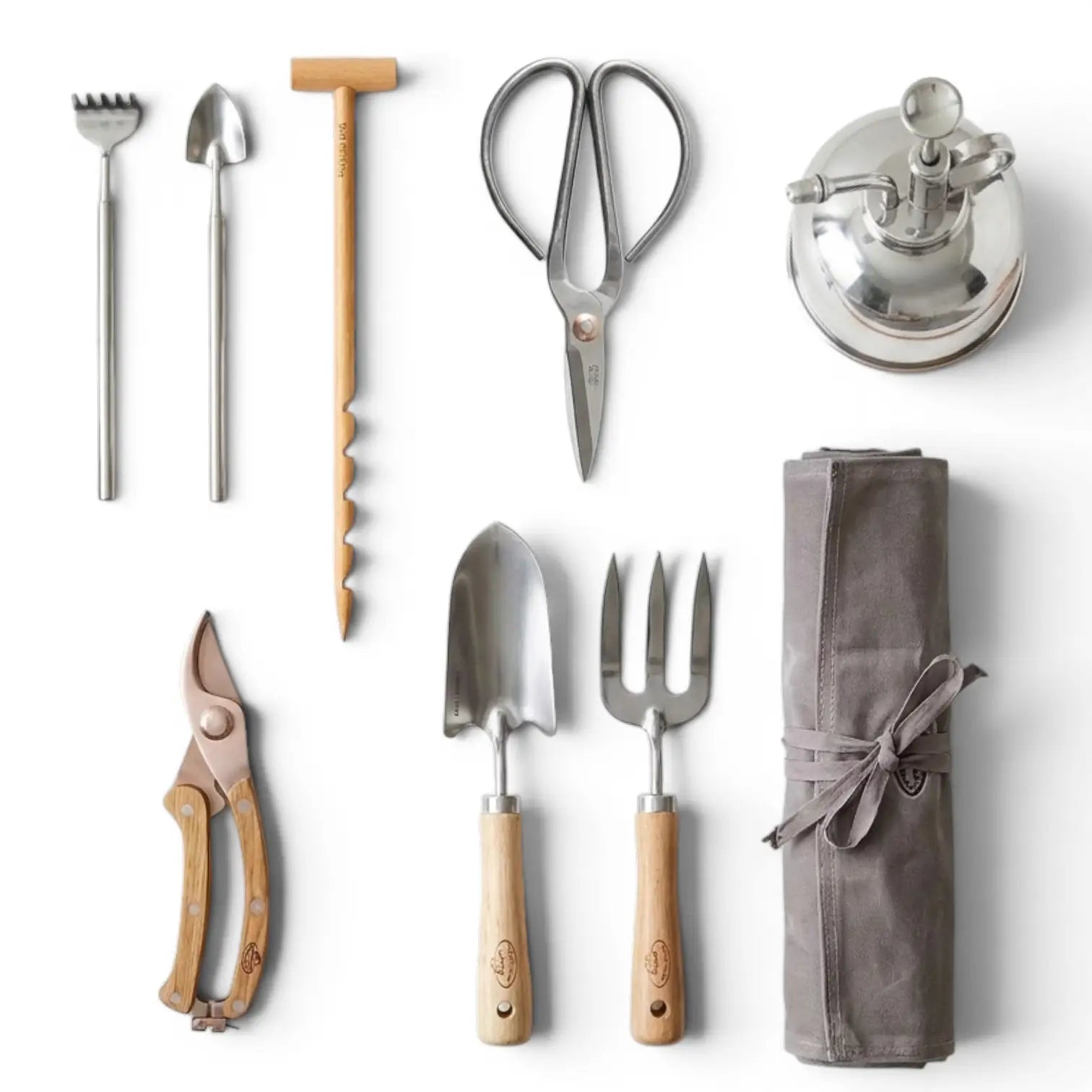 Verschiedene Pflanzwerkzeuge und Zubehörteile – Schere, Mini-Rechen, Mini-Schaufel und Feuchtigkeitsmesser – als Flatlay vor weißem Hintergrund