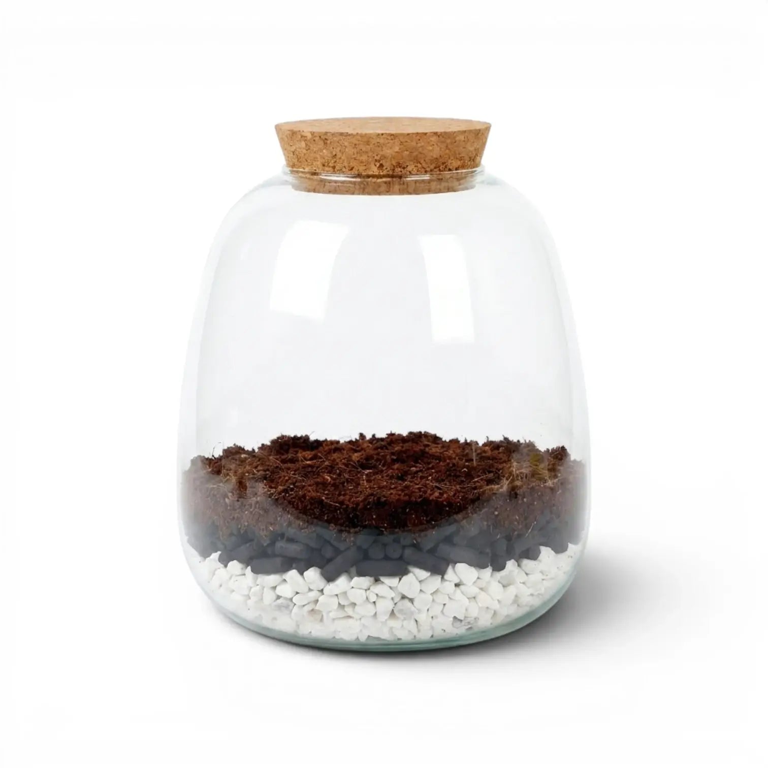 Glass jar with a cork lid containing soil, activated carbon pellets and small gravel stones on a white background